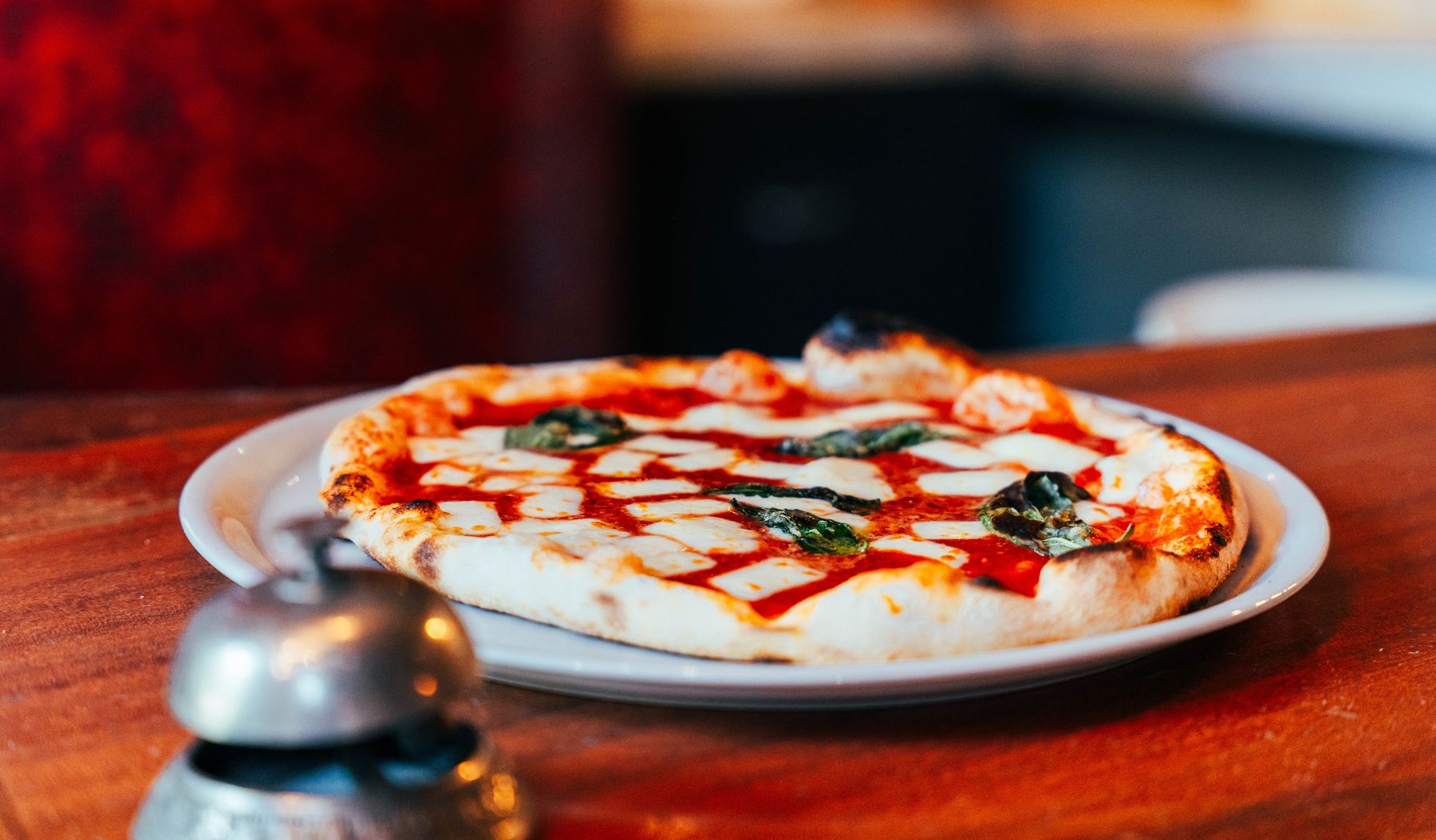 Pizza margherita au basilic frais, servie sur une nappe rouge