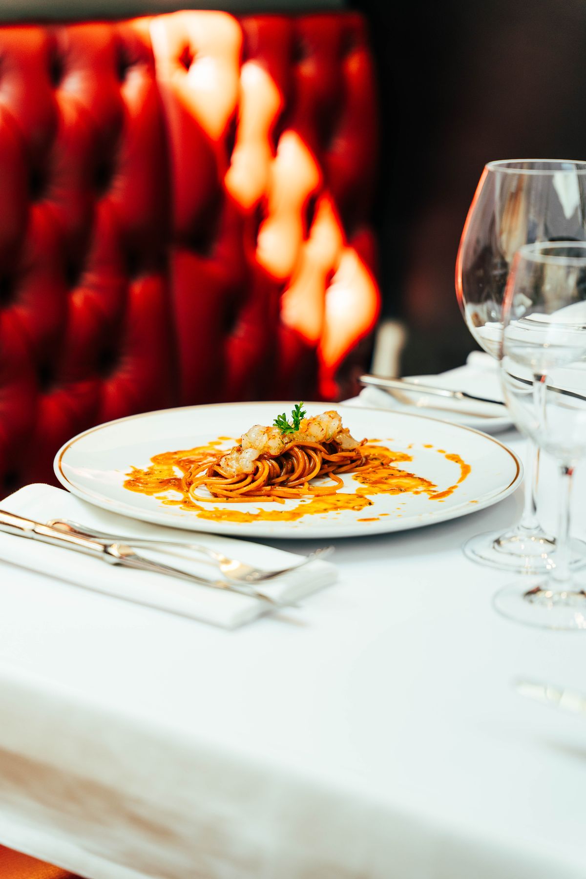 Spaghetti aux scampis servis devant une banquette capitonnée rouge